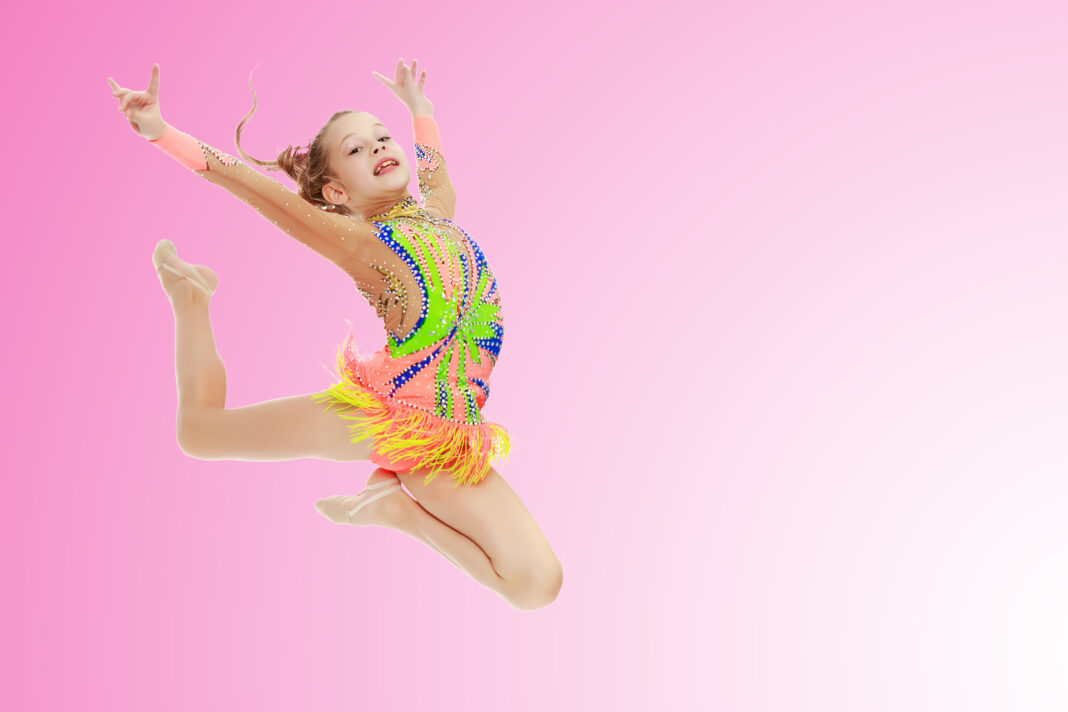 Girl gymnast performs a jump.